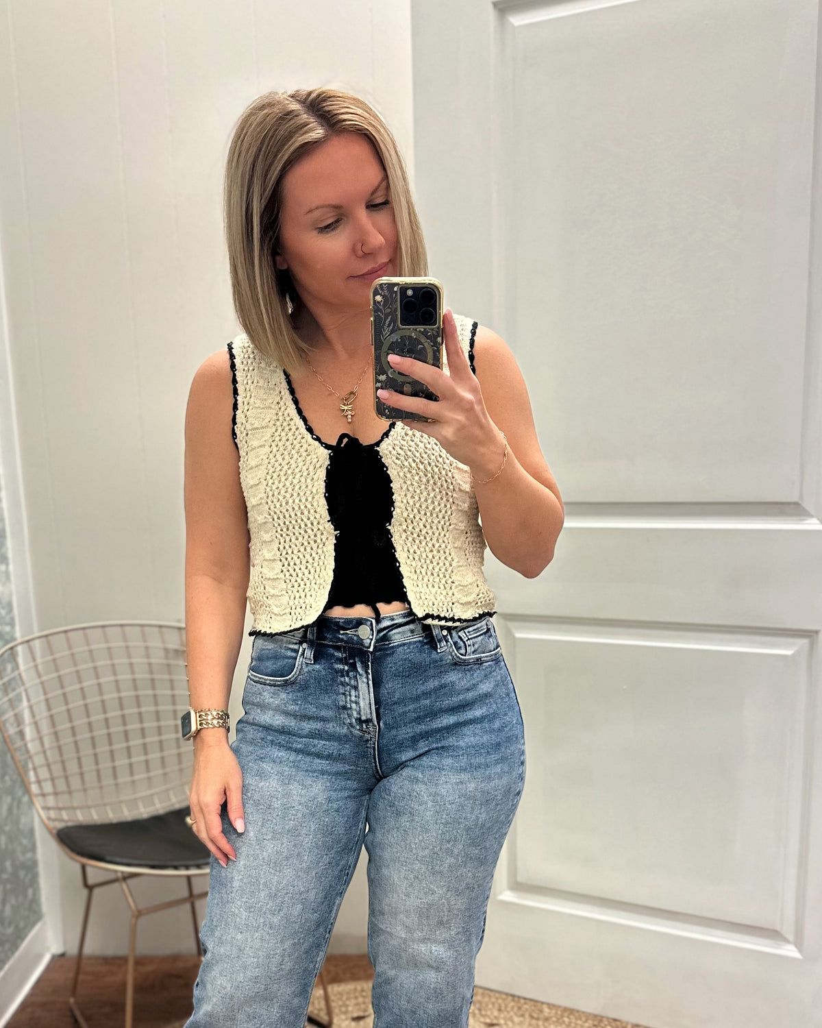 Cream crochet vest trimmed with black woven ribbon that front ties into bows. Paired with denim  jeans.